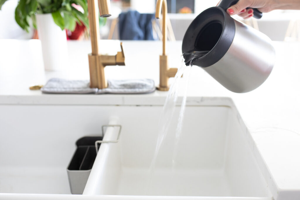 rinsing out coffee carafe into sink