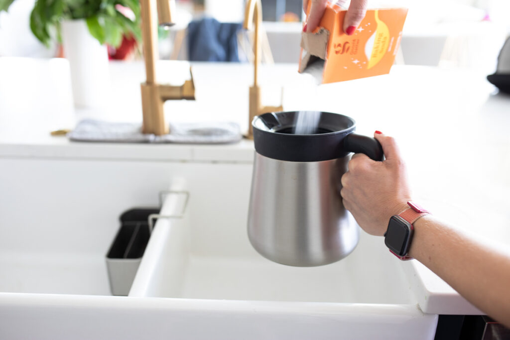 pouring baking soda into a coffee carafe