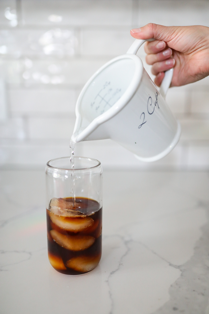 pouring water into a glass with ice and cold brew concentrate