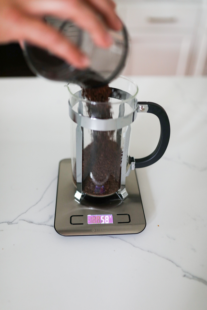 Pouring coffee grounds into a french press on a scale
