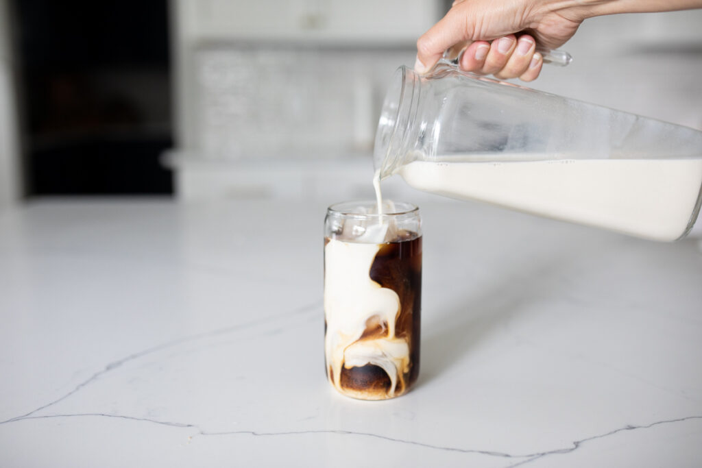 pouring oat milk into cold brew