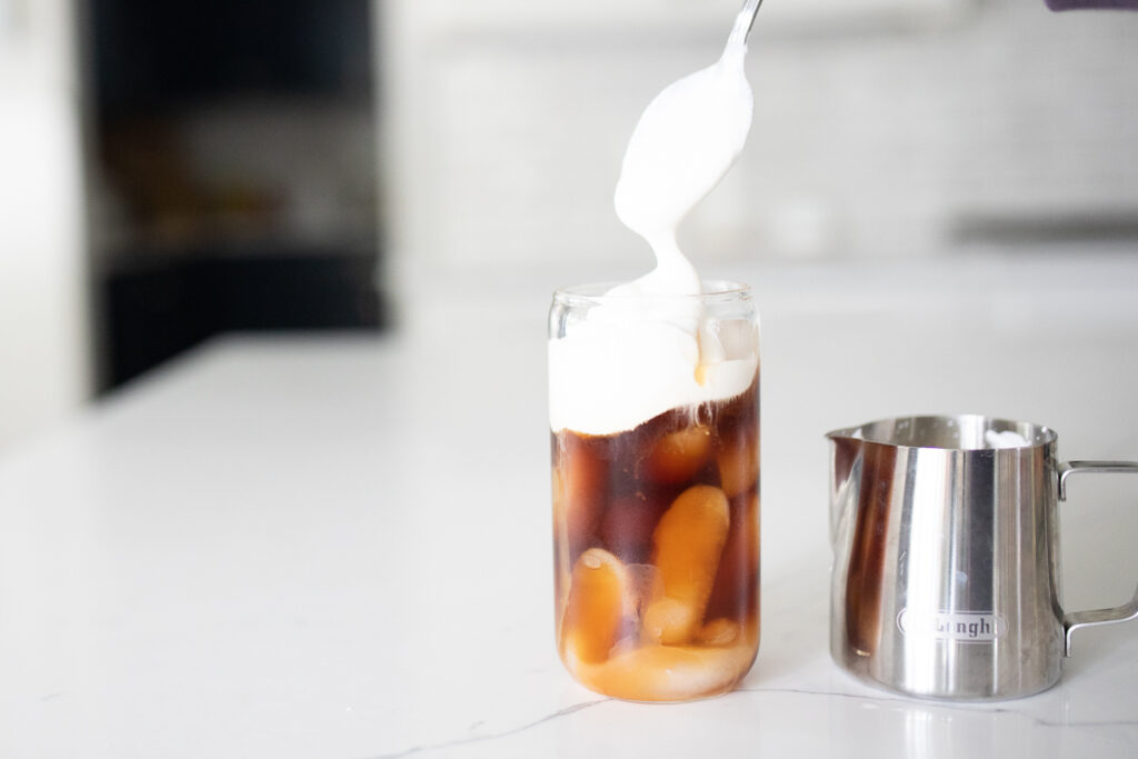 Pouring foam on top of salted caramel cream cold brew